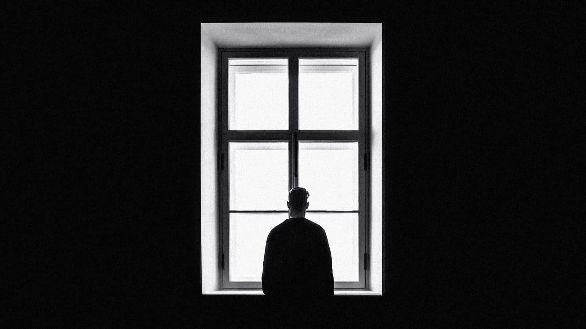 A Silhouette Of A Man Sitting In A Window