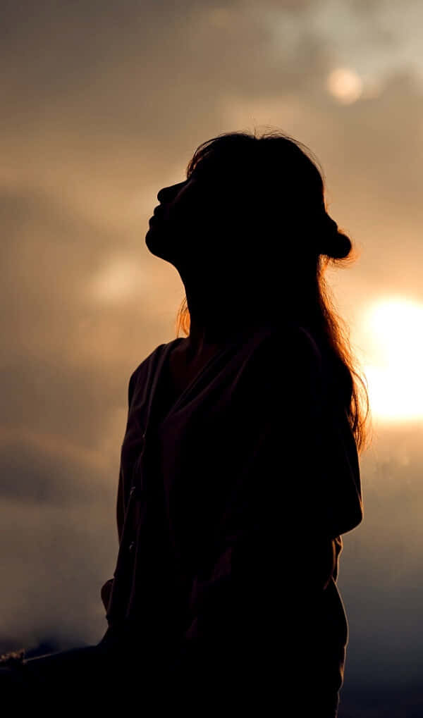 A Woman Is Silhouetted Against The Sunset
