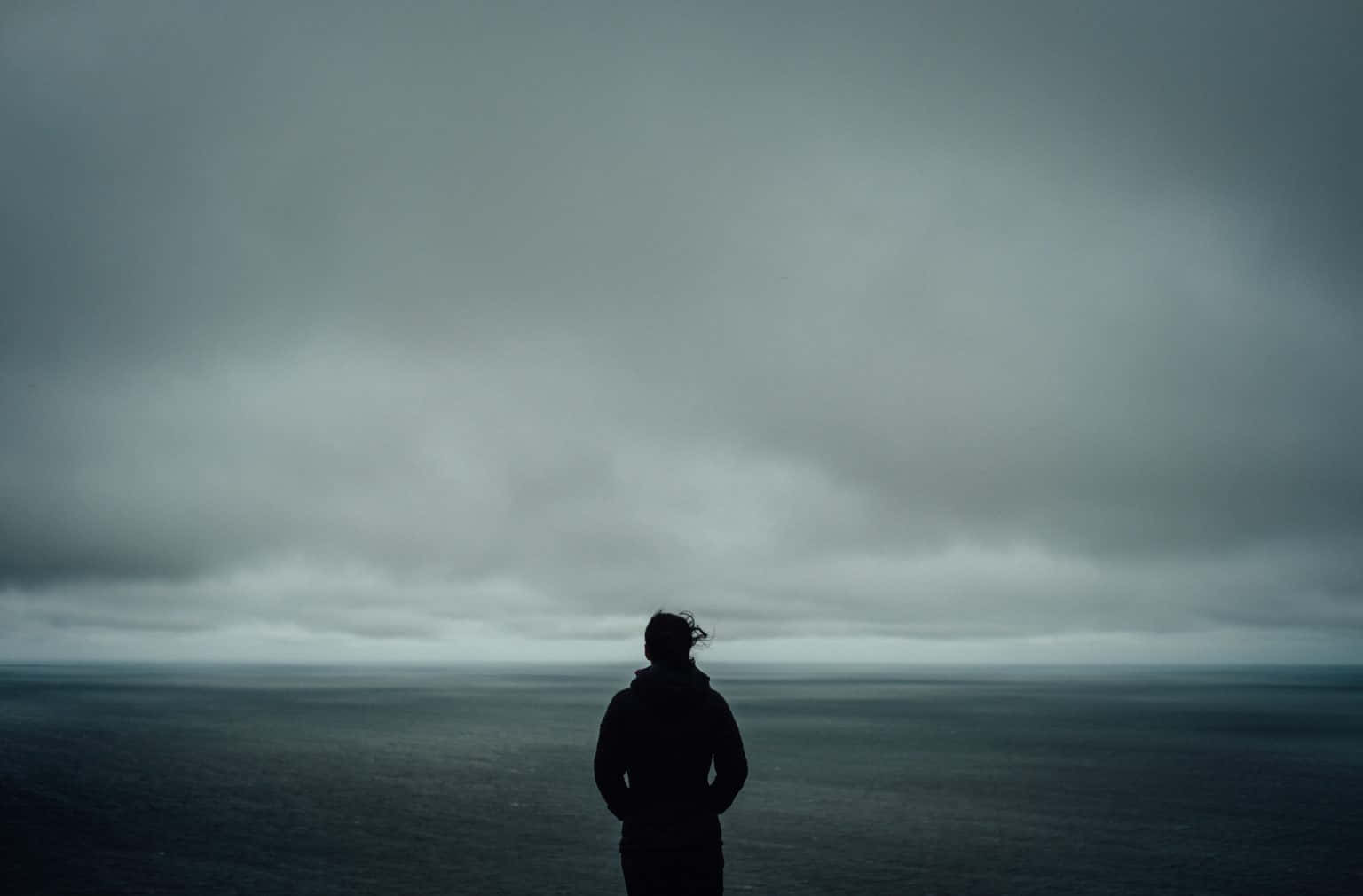 A Man Standing On A Cliff Overlooking The Ocean
