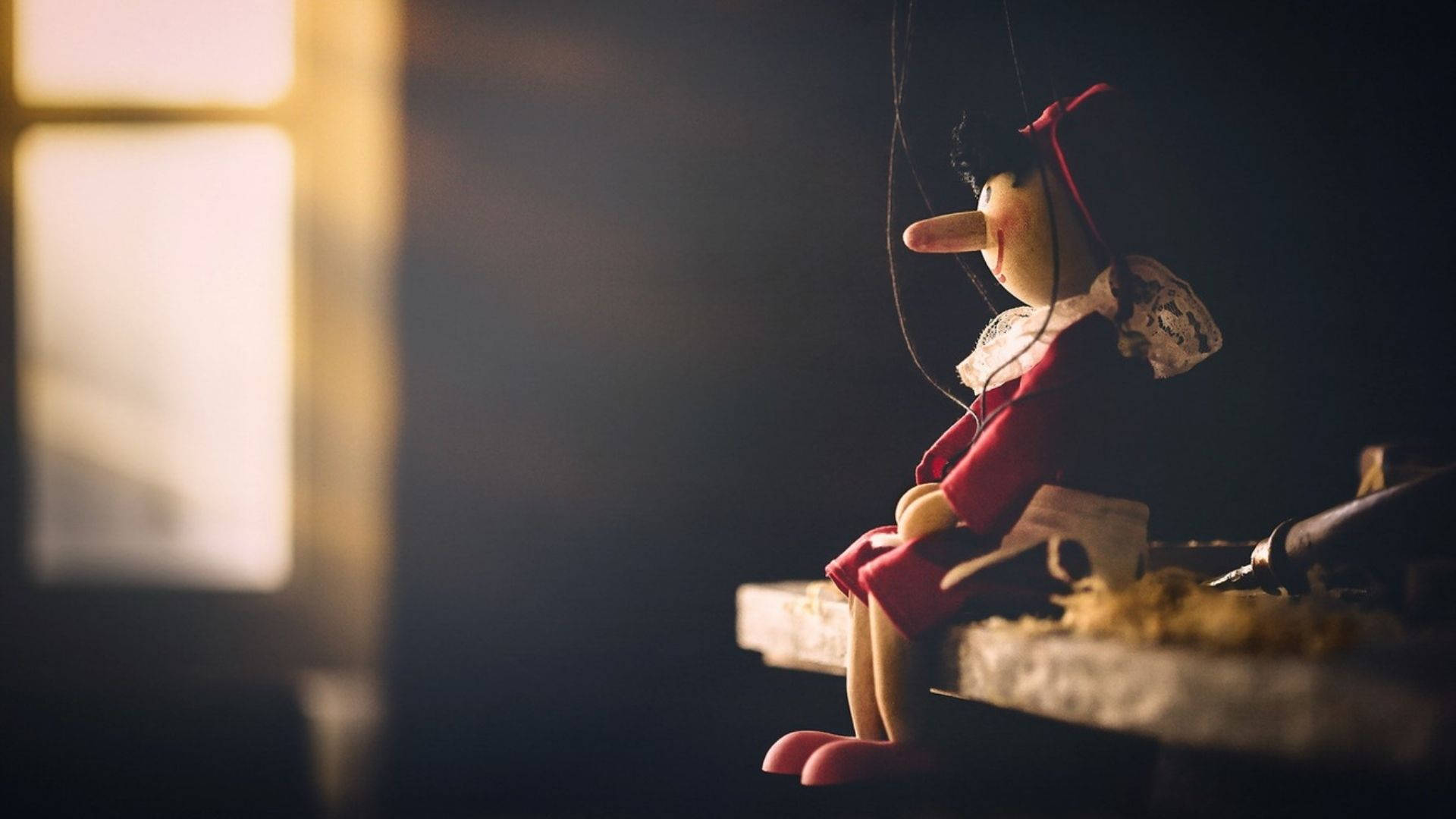 Ensom Pinocchio stirrer trist til mens han står i sin lyse karnevalsinspirerede udrustning. Wallpaper