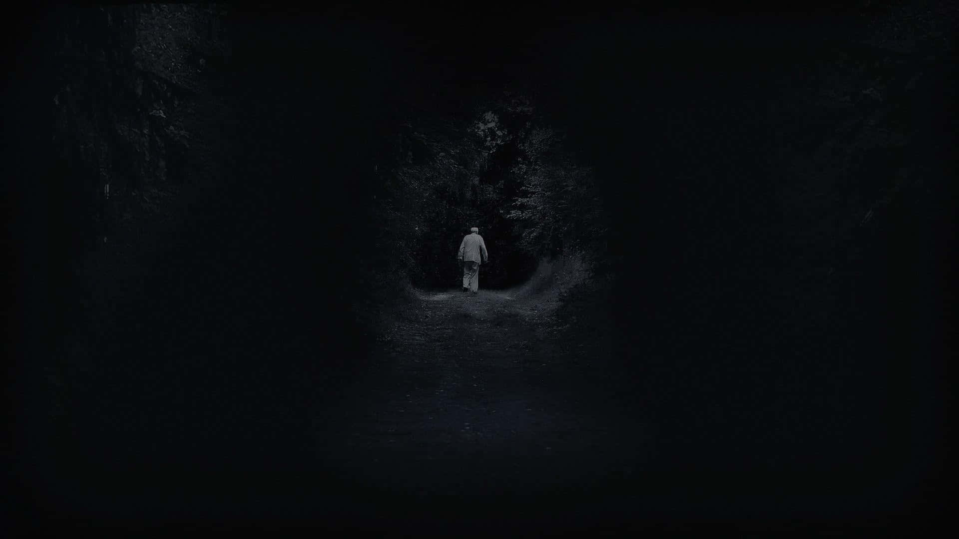 Unhombre Está Parado En La Oscuridad De Un Túnel Oscuro. Fondo de pantalla