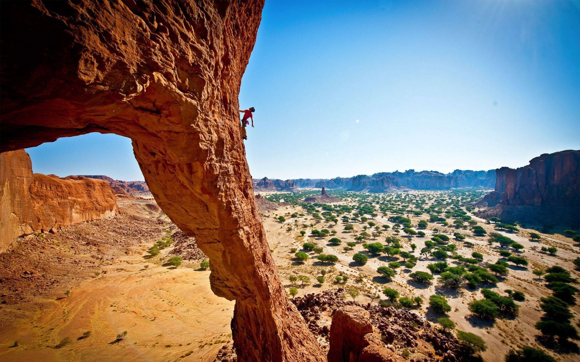 Fotoa Larga Distancia De Un Hombre Escalando Una Roca Fondo de pantalla