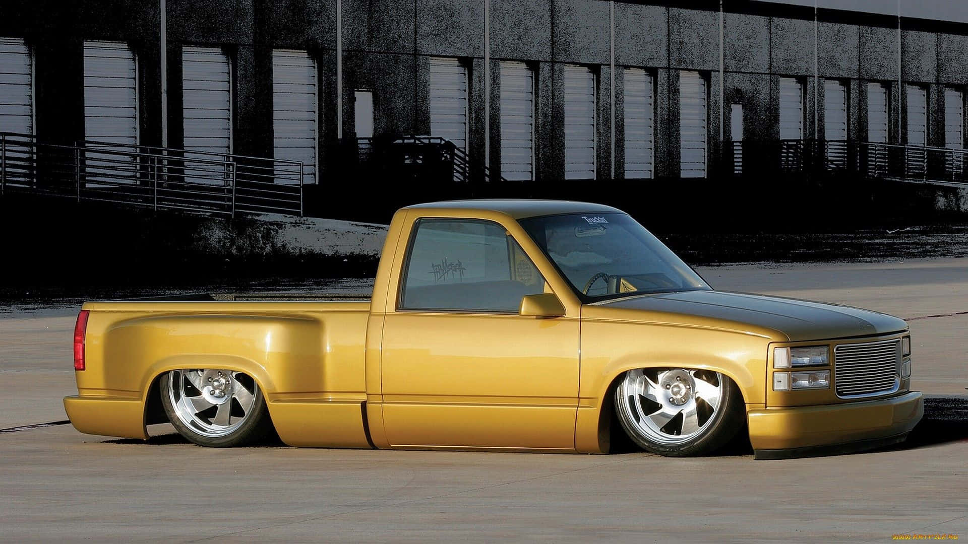 En gul lastbil parkeret i en parkeringsplads Wallpaper