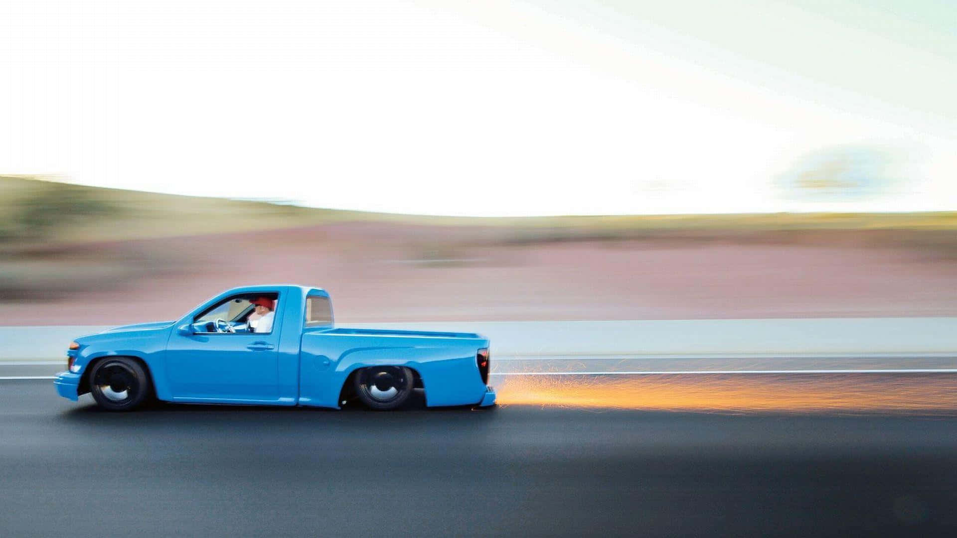 A Blue Pickup Truck Driving Down The Road Wallpaper