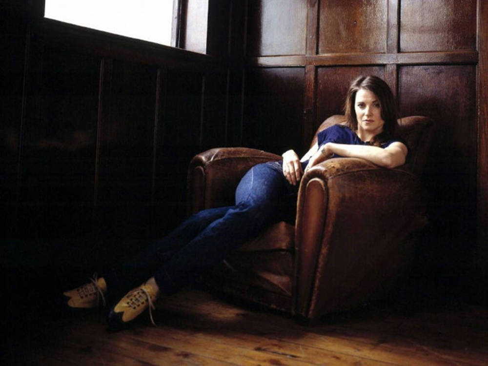 Lucy Lawless On Brown Couch Wallpaper