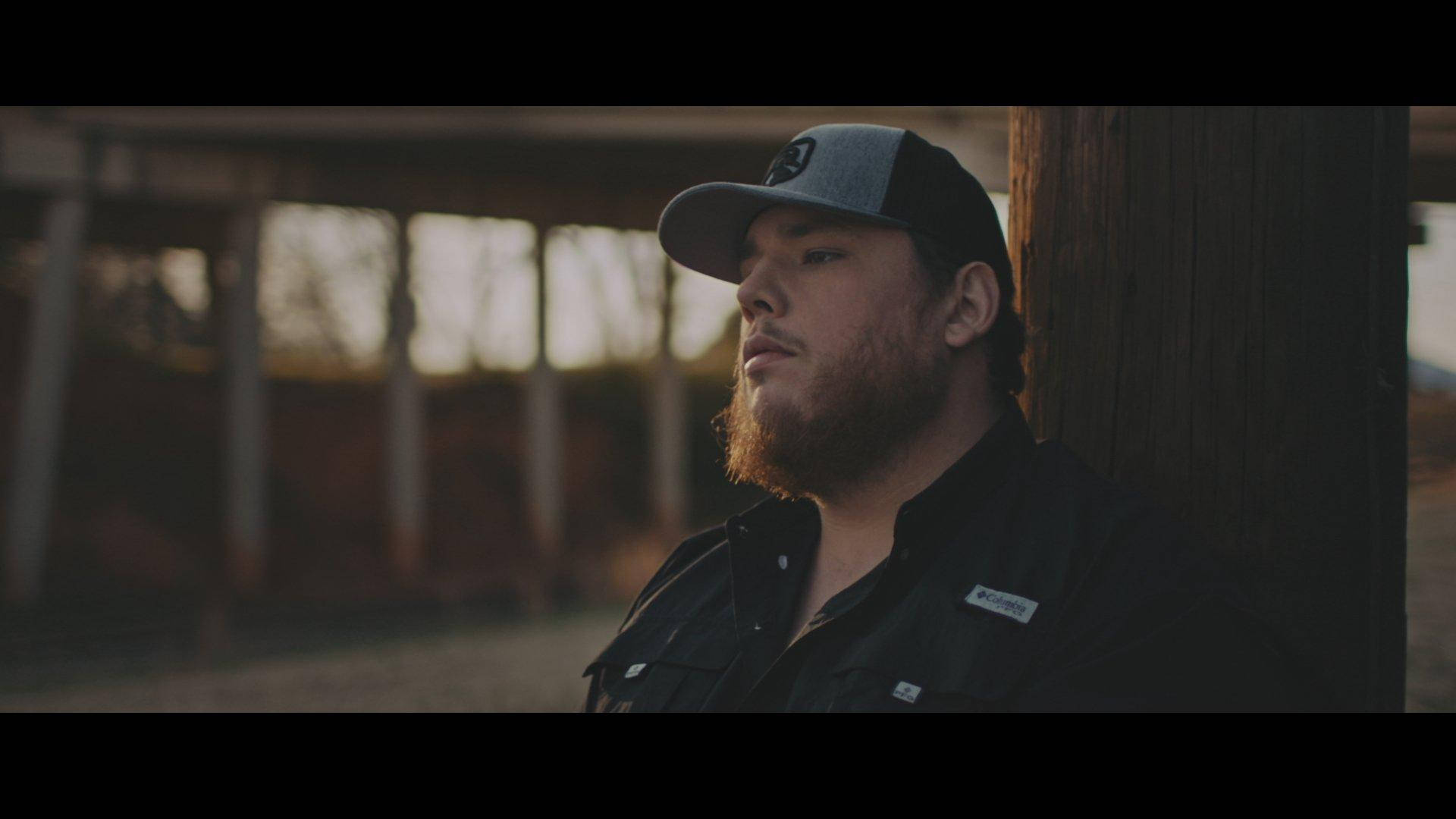 Musician Luke Combs performing on stage with a classic America flag background Wallpaper