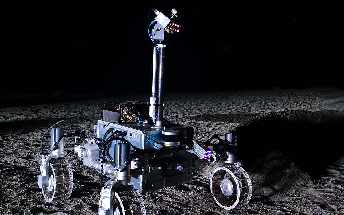 Astronautaconduce Un Rover Lunar En La Superficie De La Luna. Fondo de pantalla