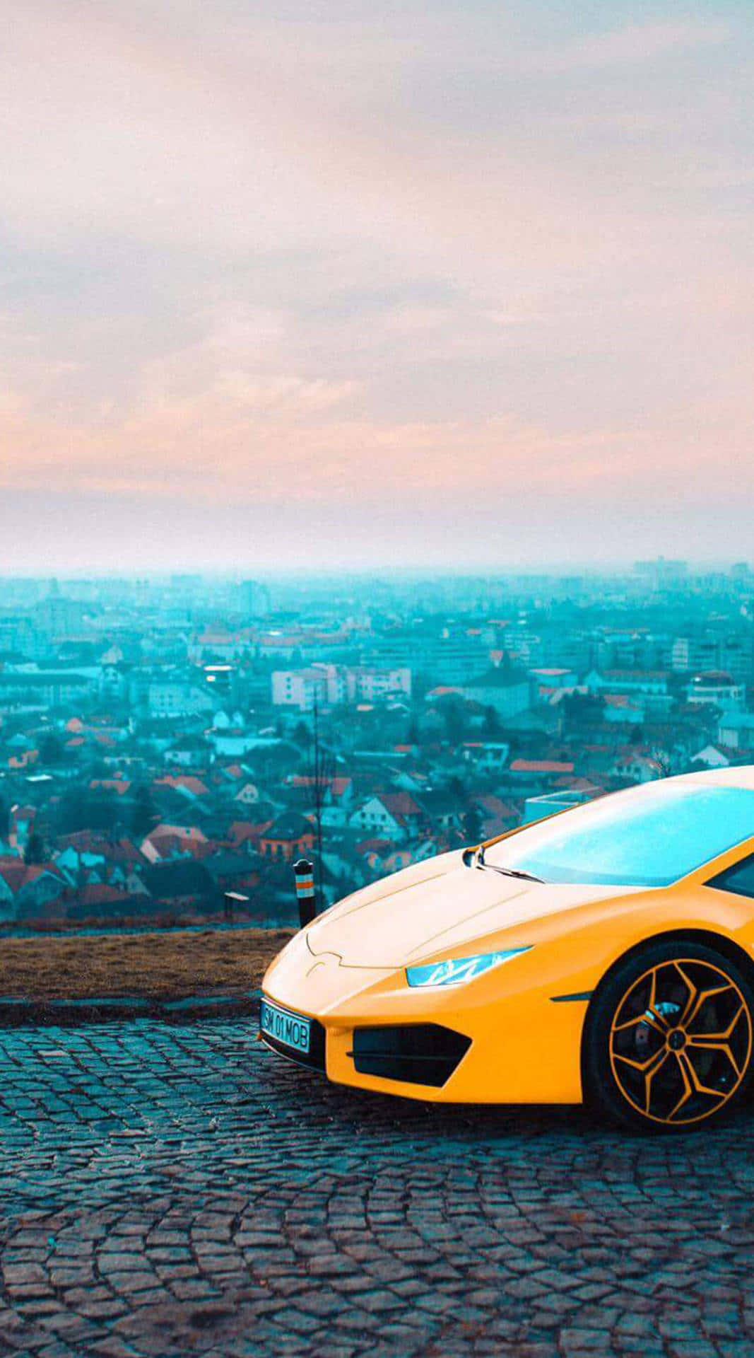 A Yellow Sports Car Parked On A Cobblestone Street Wallpaper