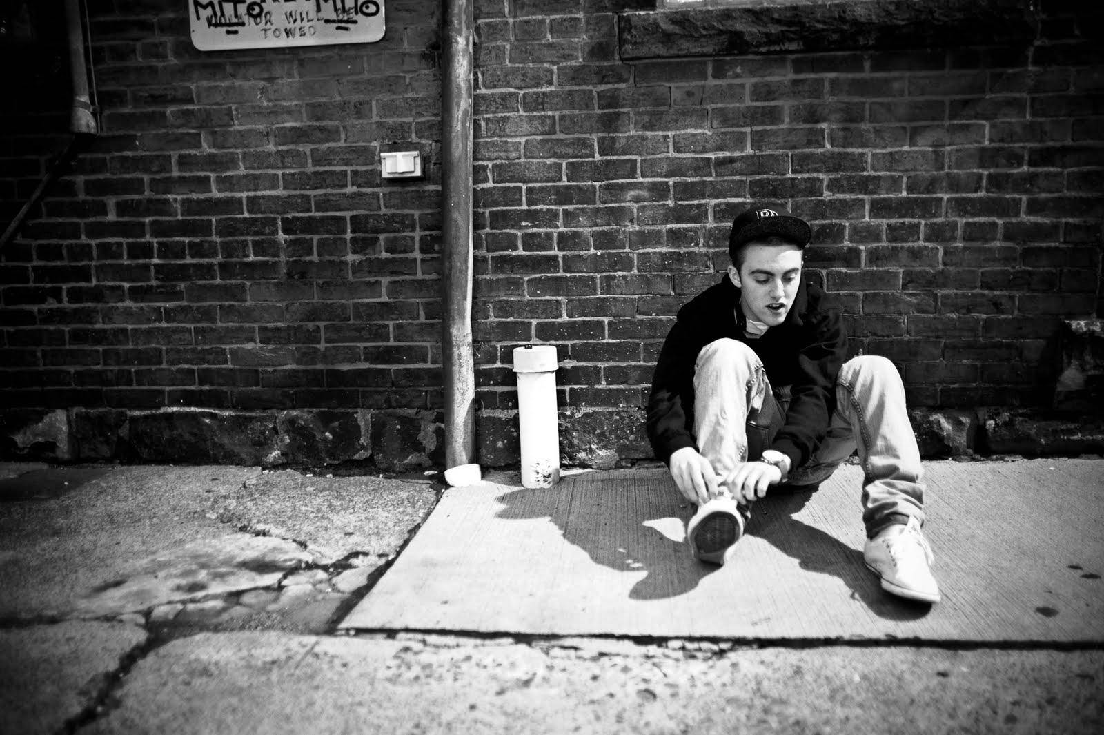 Mac Miller Fixing Shoes In Alley Wallpaper