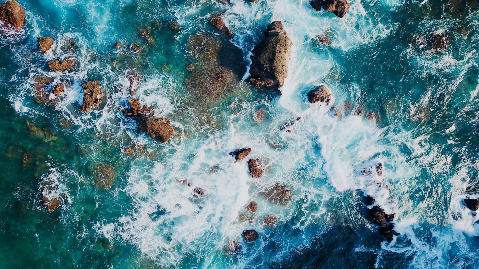 Aerial View Of Ocean Waves Crashing On Rocks Wallpaper