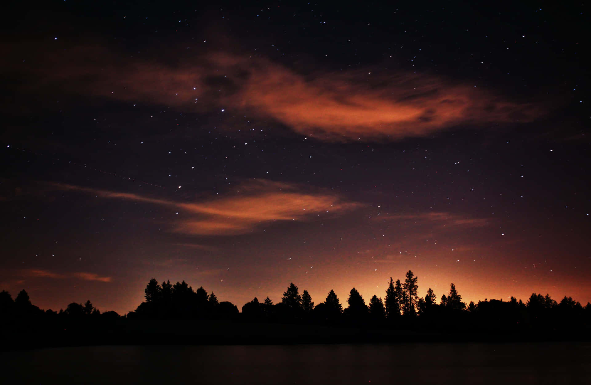 Magical Night Sky With Silhouette Of Trees With Clouds And Stars Wallpaper