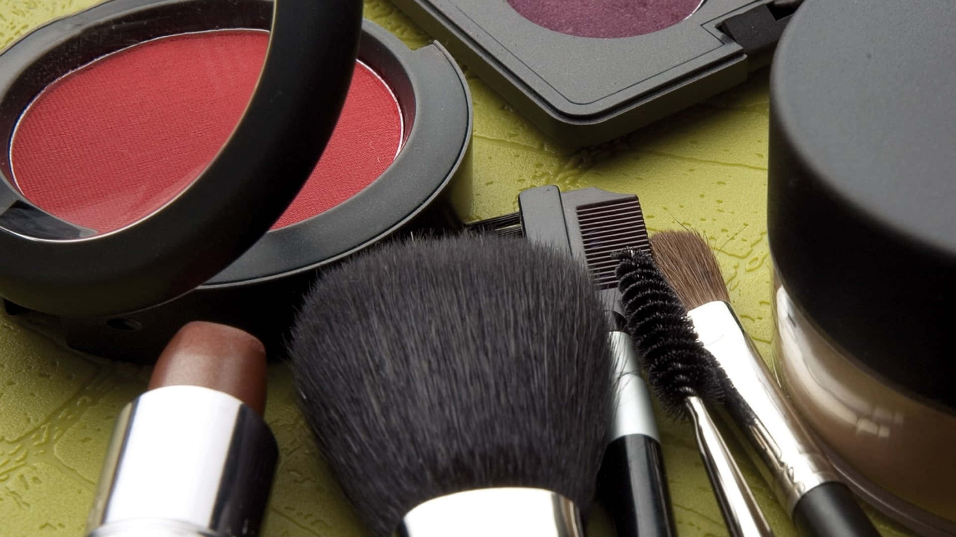 Cosmetics And Makeup Brushes On A Green Surface