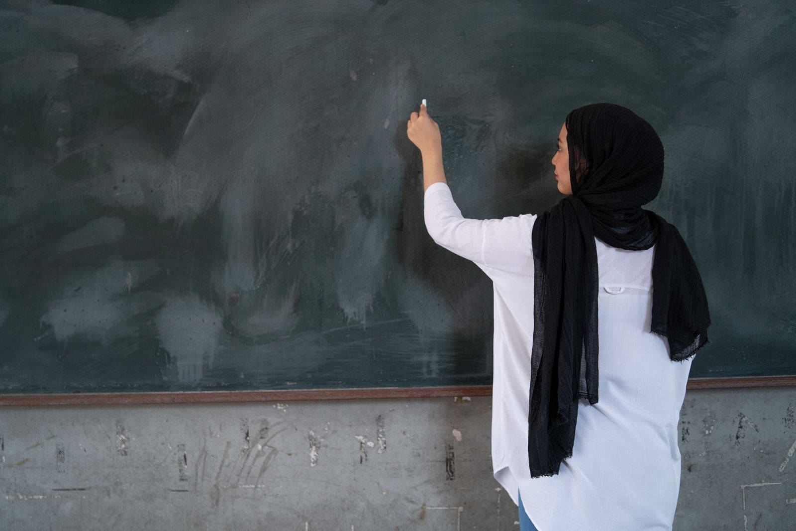 Malaysian Teacher Writing On Blackboard Background