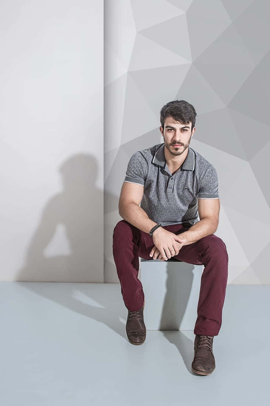 Confident Male Model Posing Against Abstract Gray Wall Wallpaper