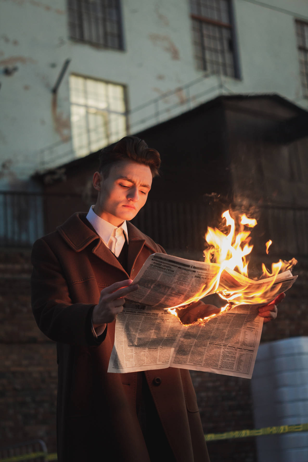 Caption: Daring Stylish Man Holding a Burning Newspaper Wallpaper