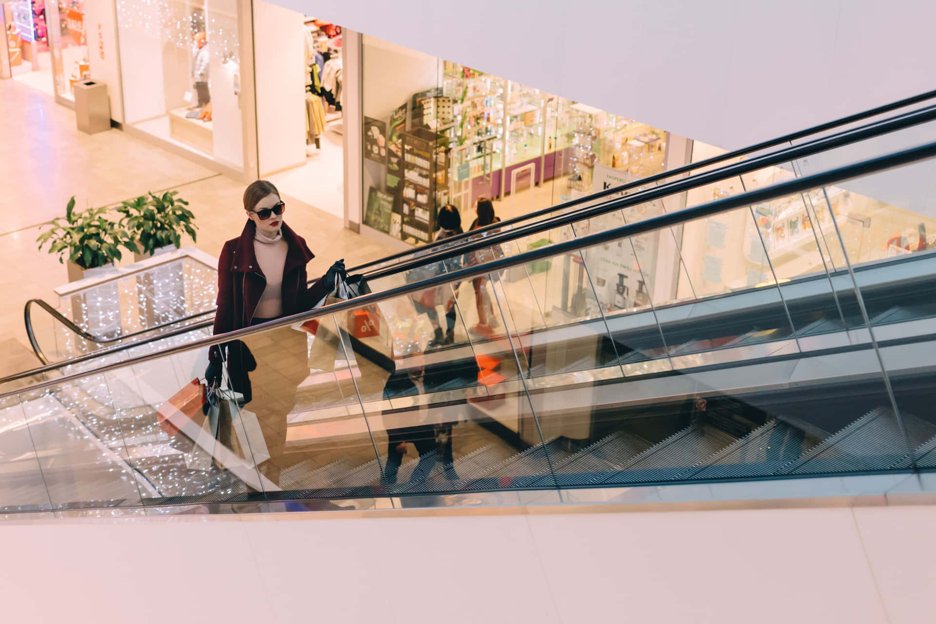 A Woman Is Walking Down An Escalator In A Shopping Mall