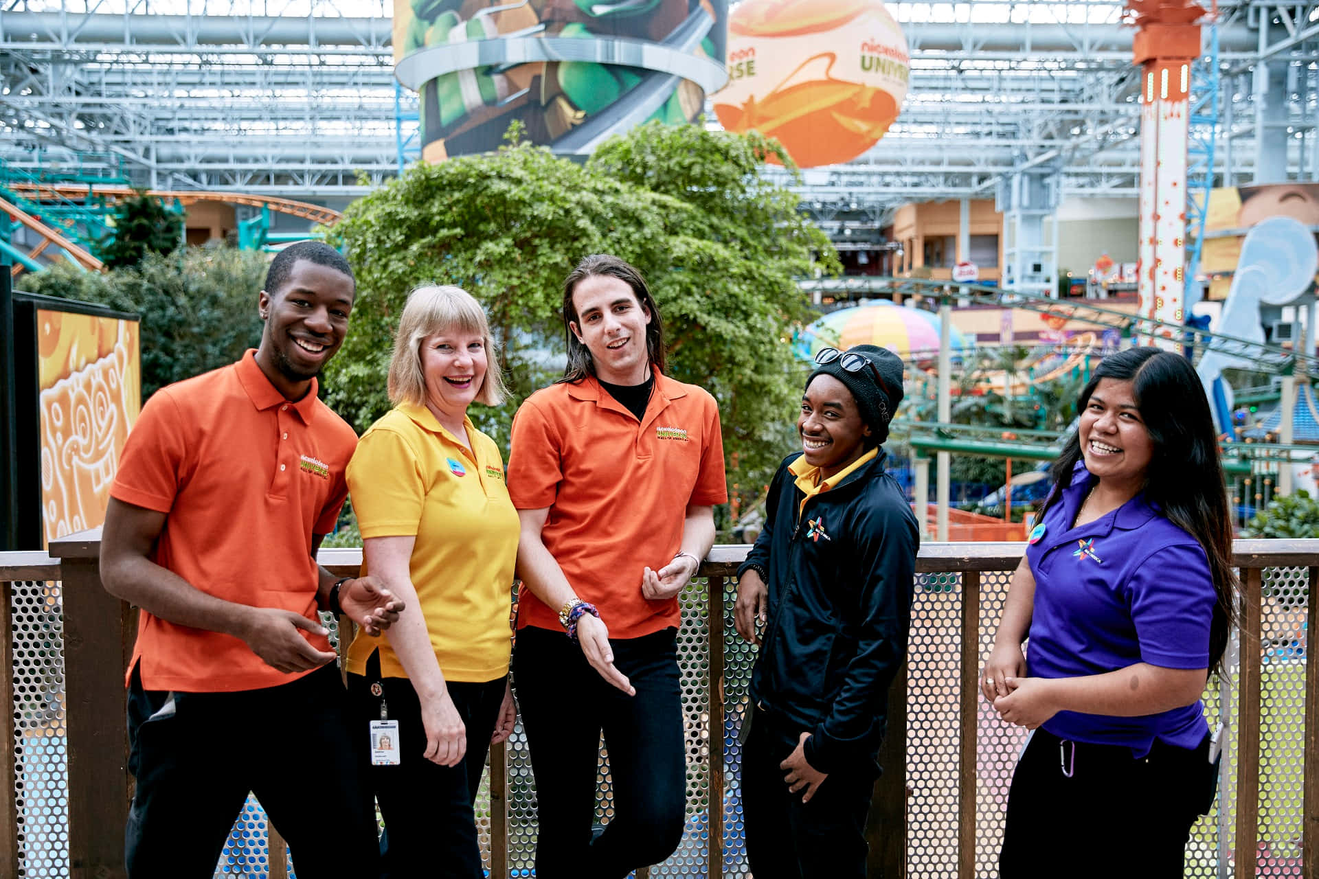 Four People In Orange Shirts Standing In A Mall