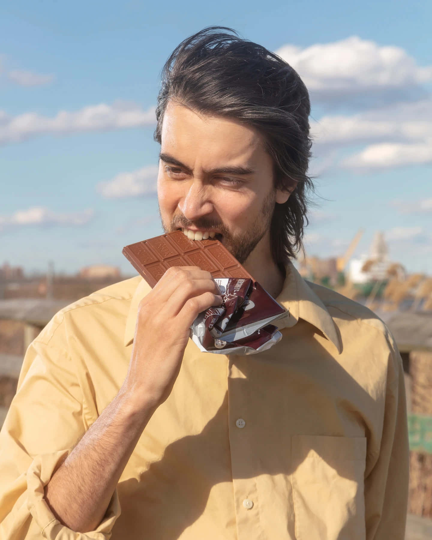 Man Biting Chocolate Bar Outdoors Wallpaper