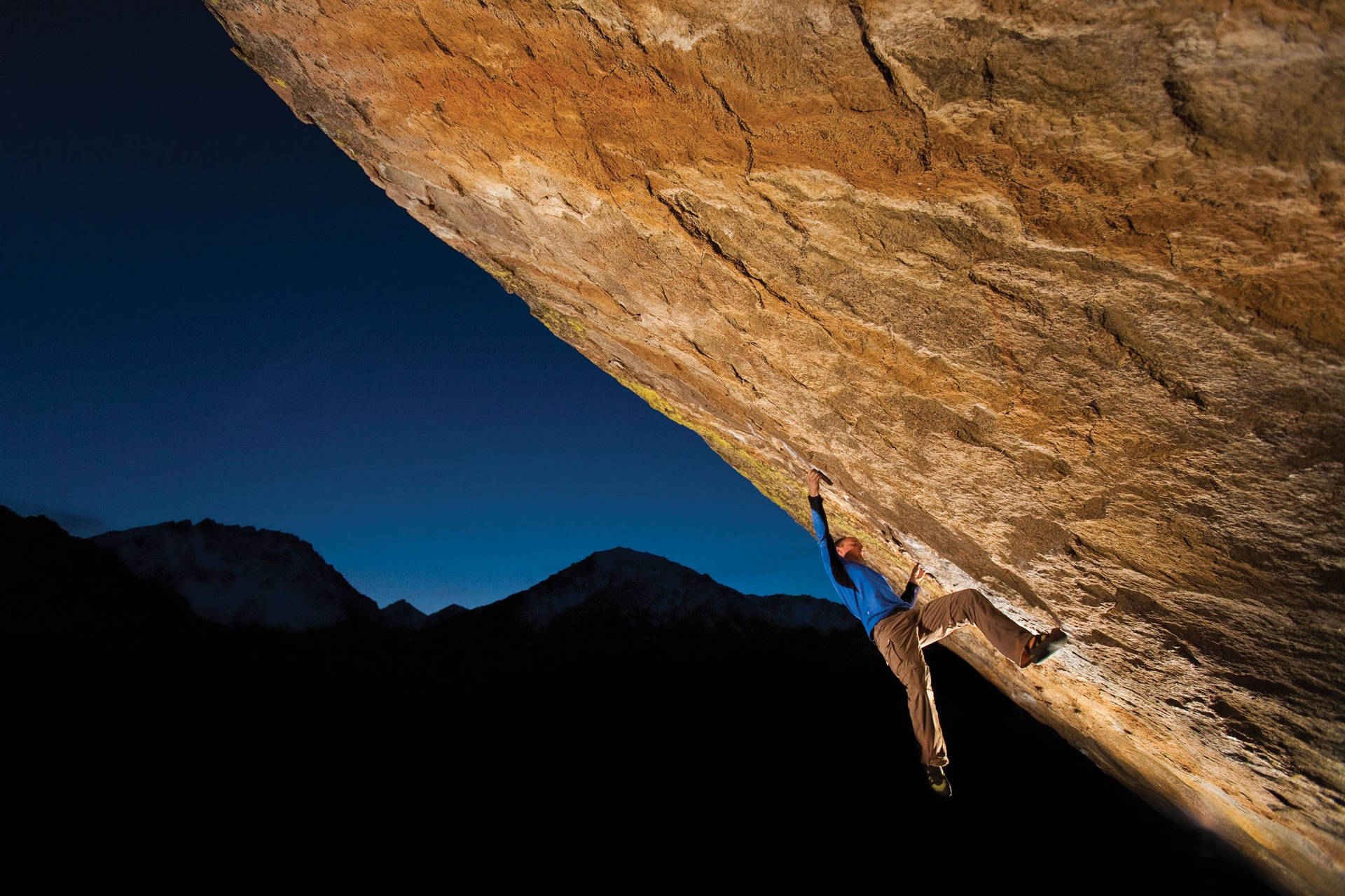 En mand klatrer på en stor klippe om natten Wallpaper