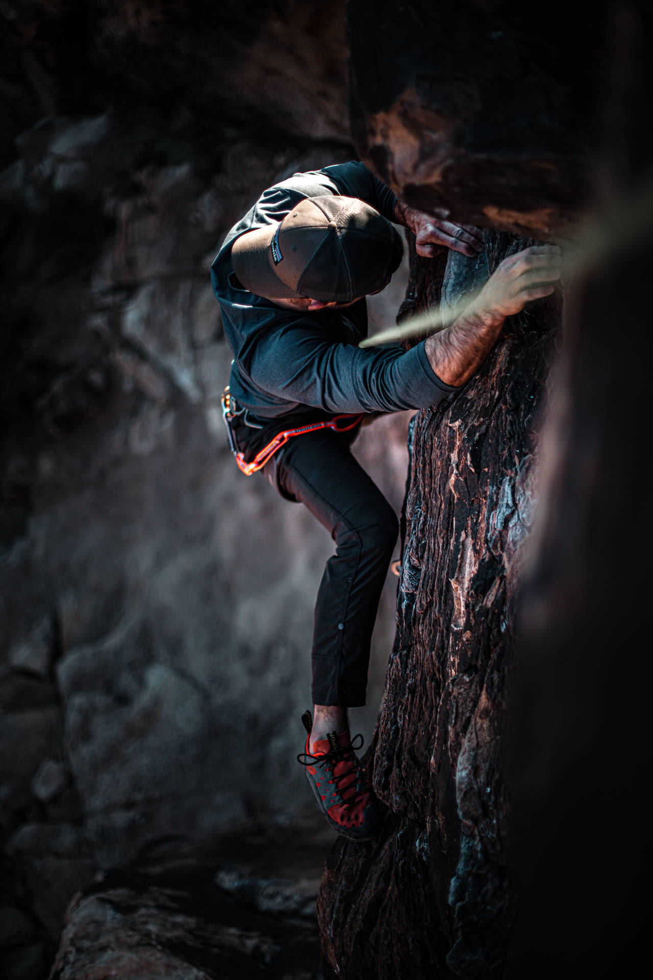 Man Climbing On A Dark Rock Structure Wallpaper