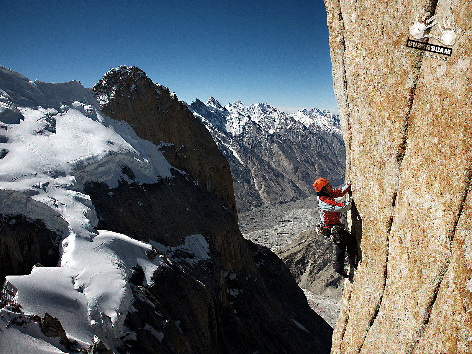 Man Climbing On A Snowy Rock Mountain Wallpaper