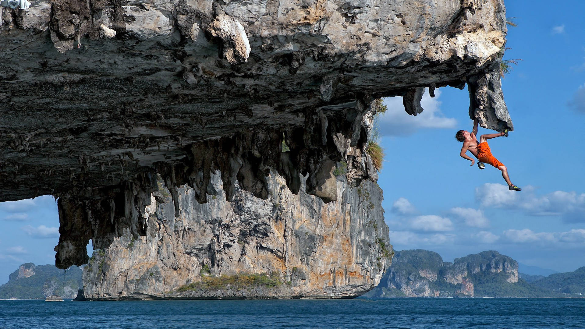 Hombreescalando Una Cueva Rocosa Cerca Del Océano Fondo de pantalla