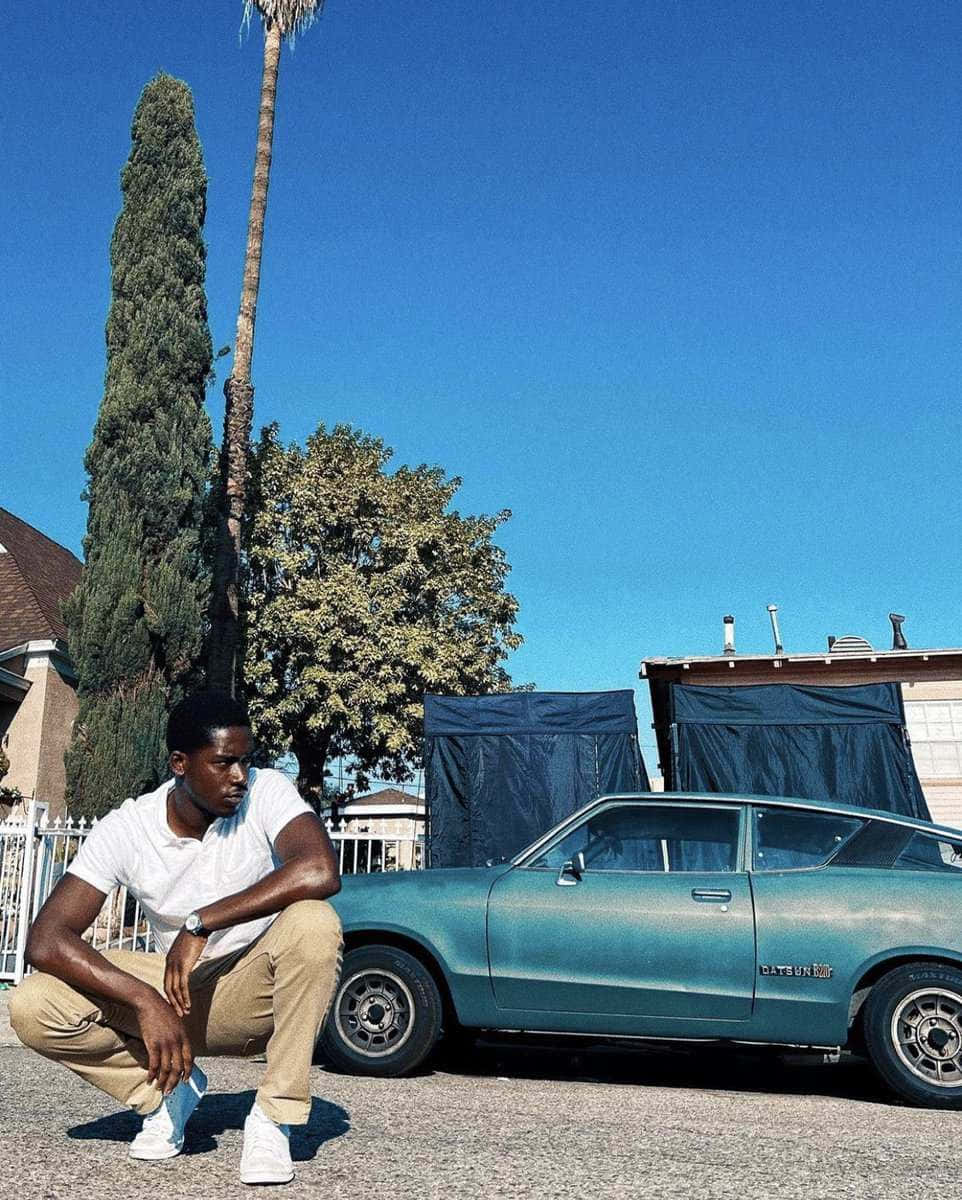 Man Crouching Beside Vintage Car Wallpaper