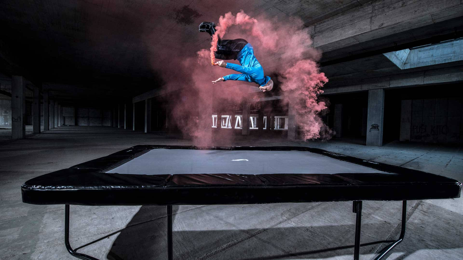 Mannvollführt Einen Akrobatischen Sprung Auf Einem Trampolin Mit Rauch Wallpaper