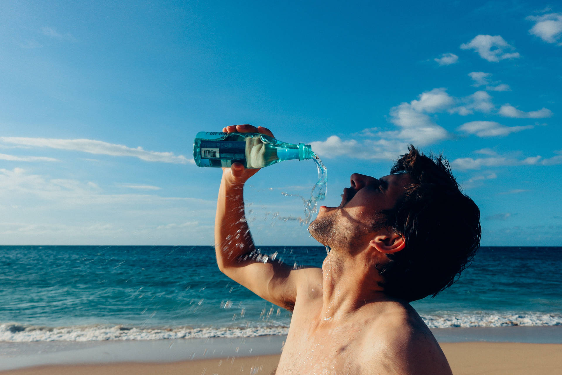Download Man Drinking Water By The Sea Wallpaper 