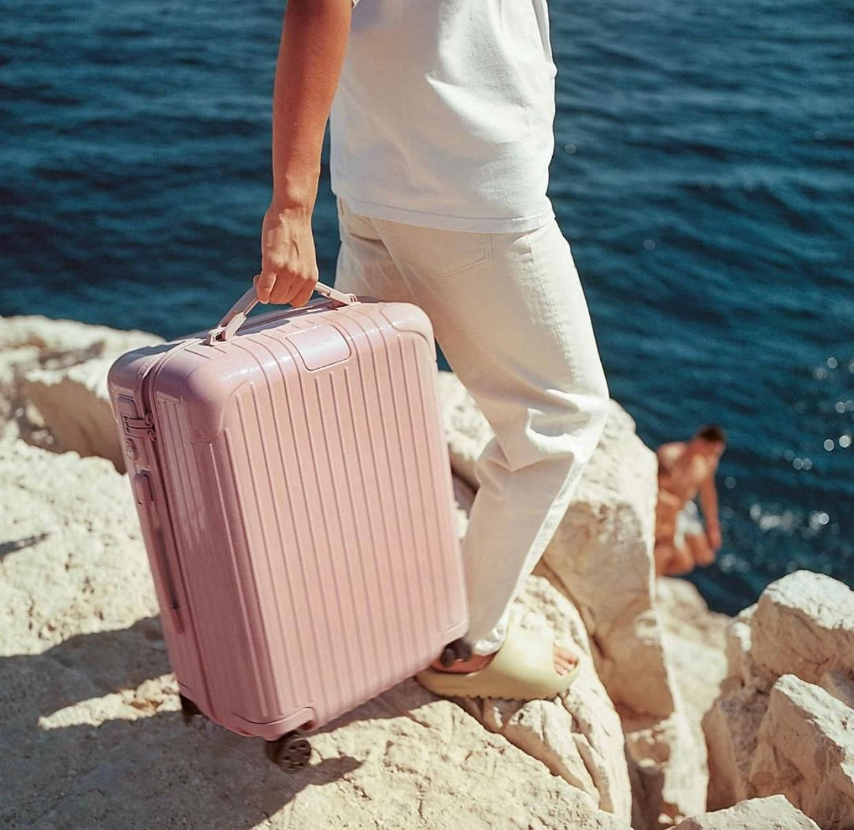 Man Holding Desert Rose Rimowa Suitcase Wallpaper