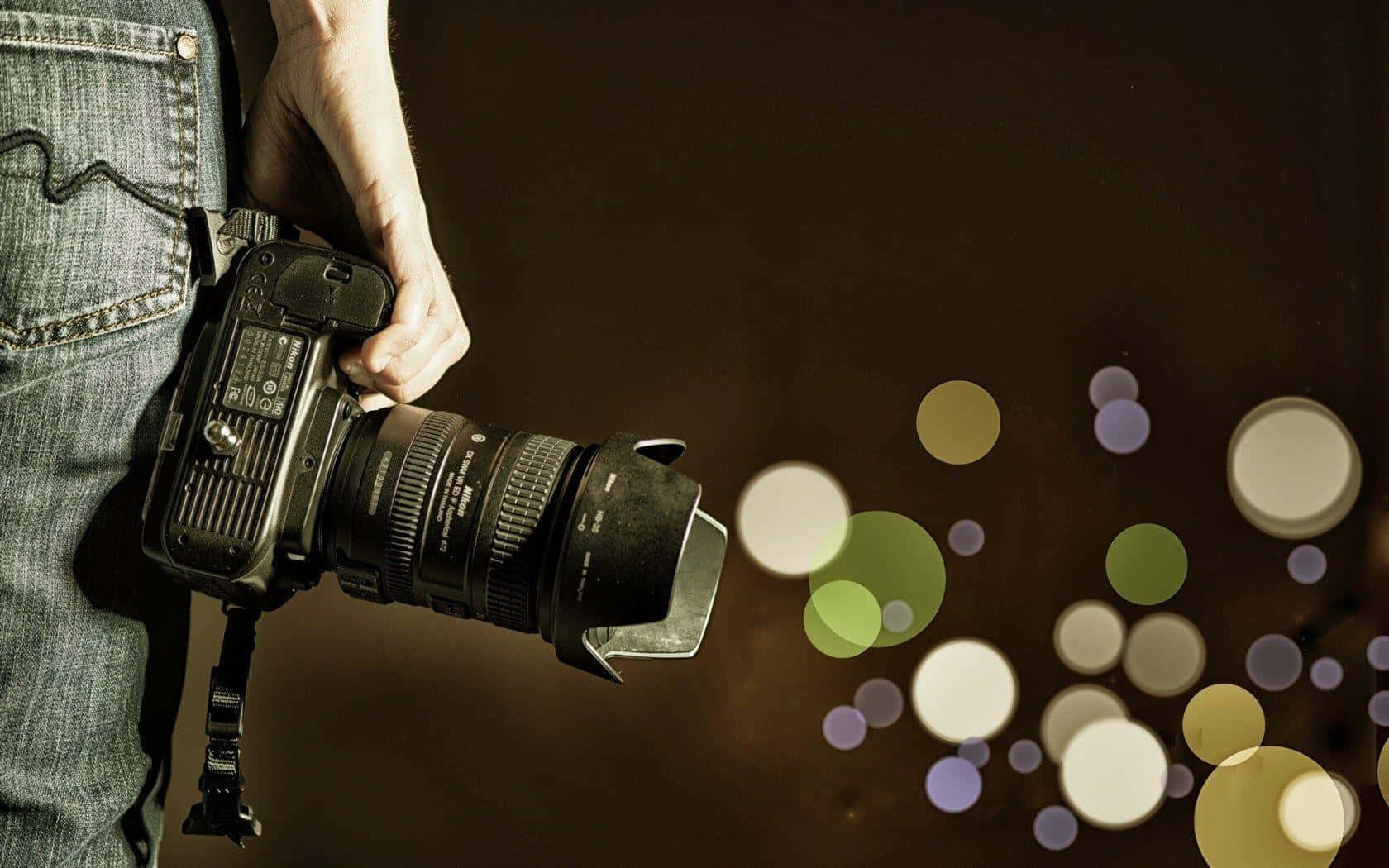 Mannhält Fotokamera In Verschwommenem Licht. Wallpaper
