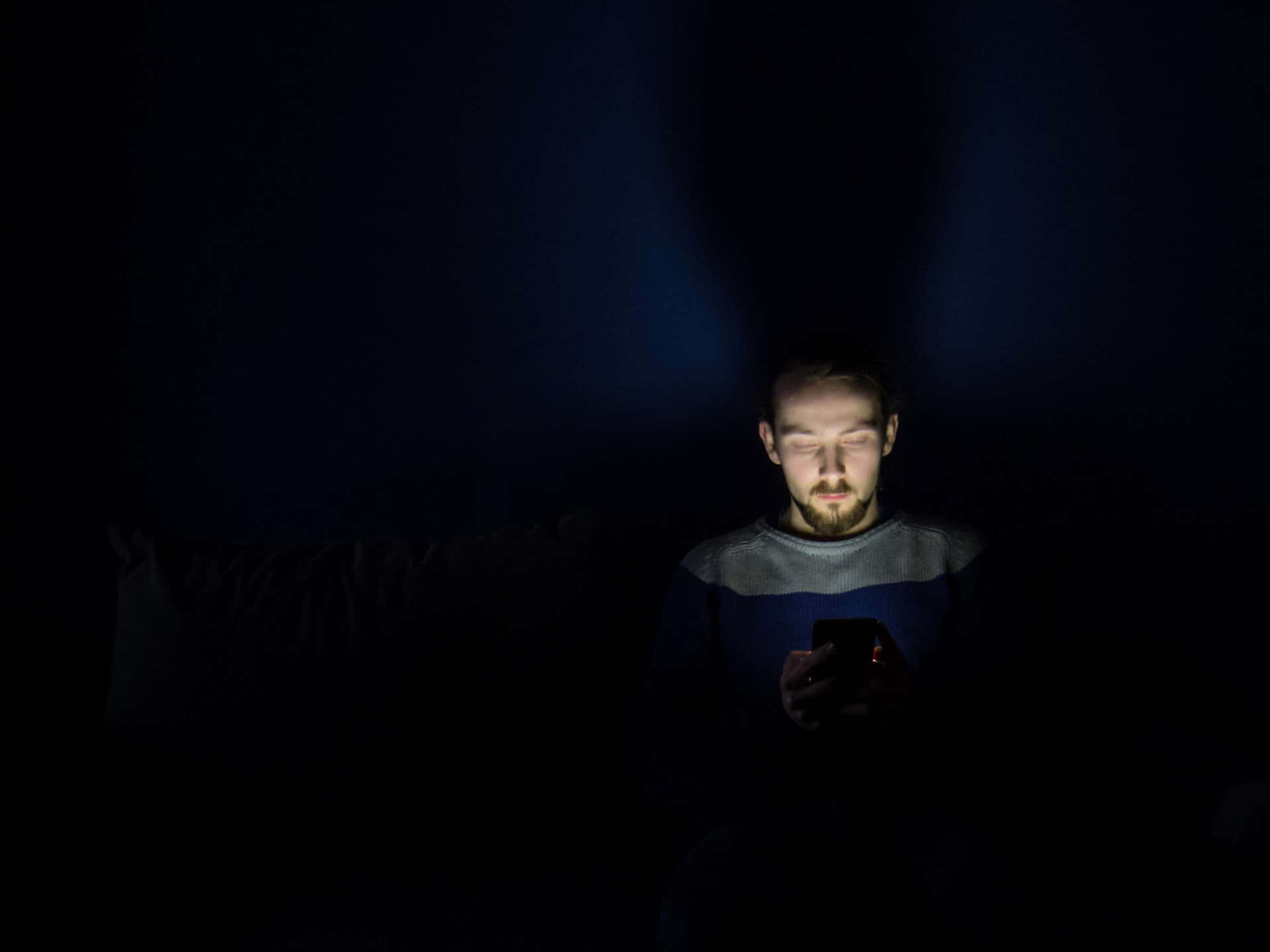 Man In Dark Room With Smartphone Addiction Wallpaper