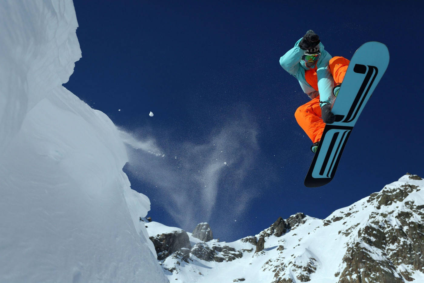 Man In Orange Descending With A Snowboard Background