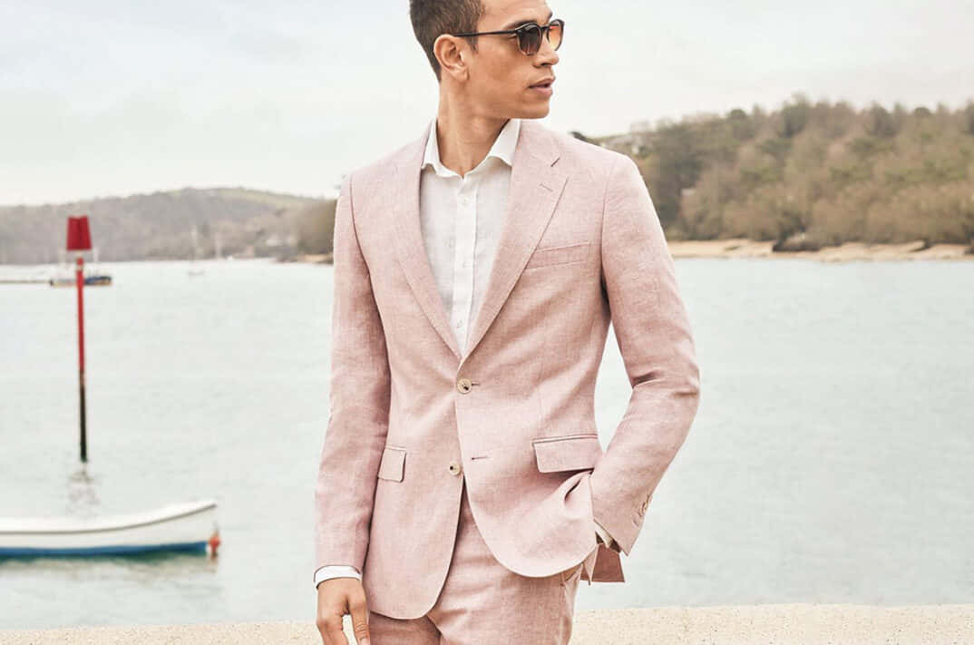 A Man In A Pink Suit Standing By The Water