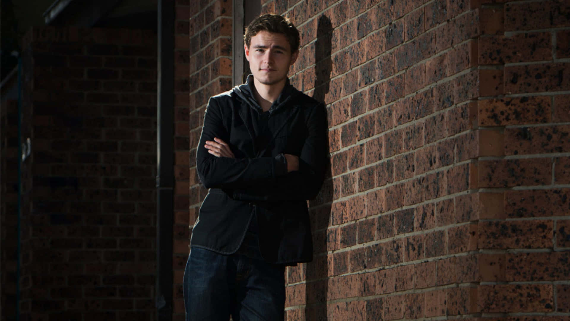 Man Leaning Against Brick Wall Wallpaper