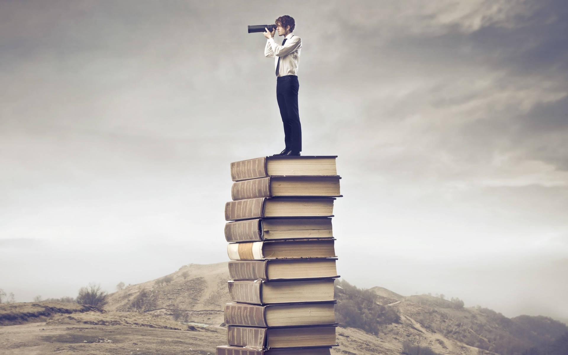 Man with spyglass standing on book stack wallpaper