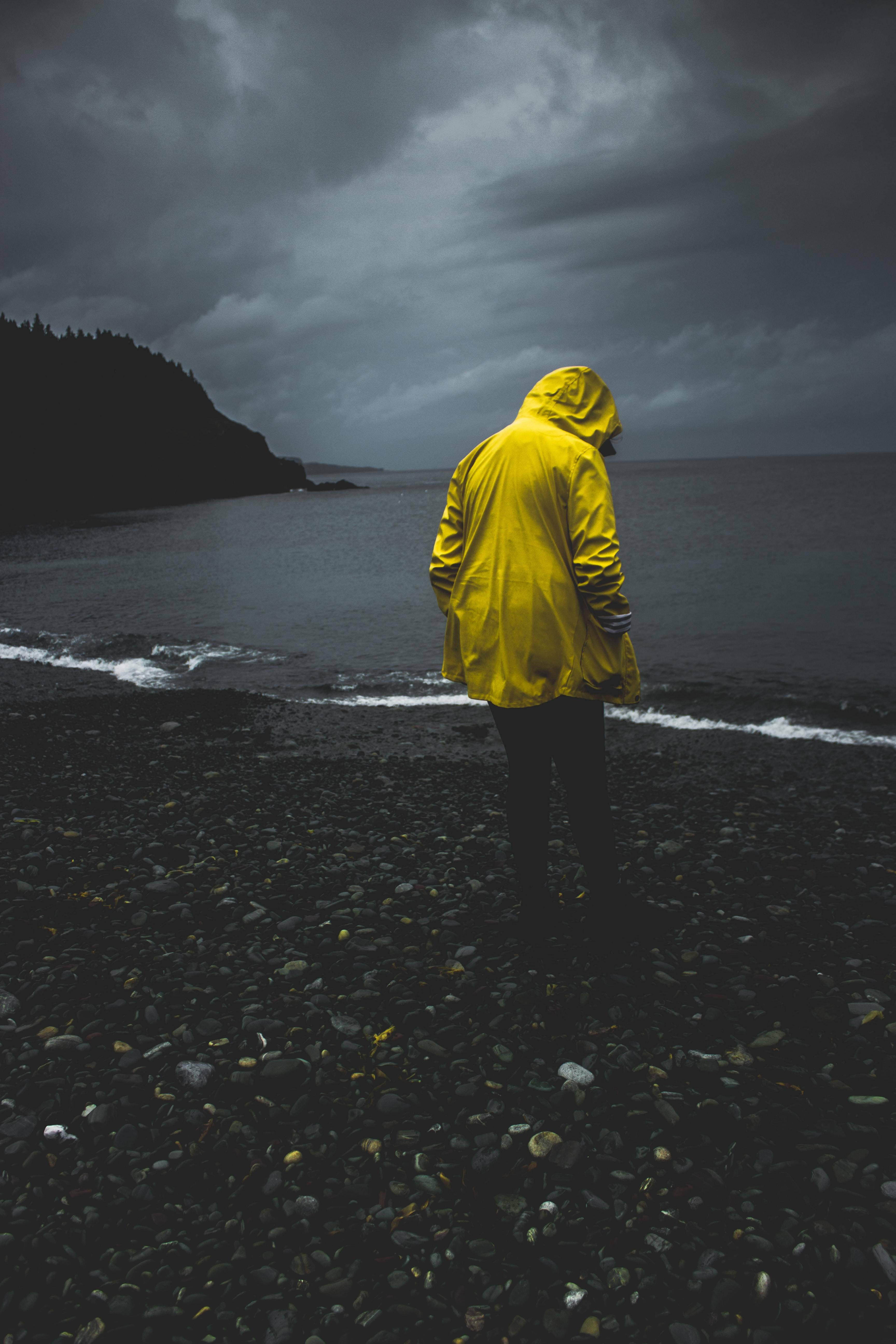 Man On Rocky Seashore Alone Phone Background