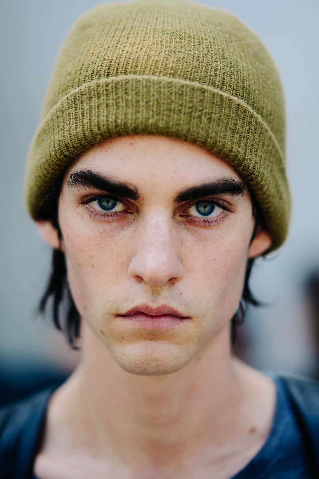 A Young Man With Blue Eyes Wearing A Green Beanie