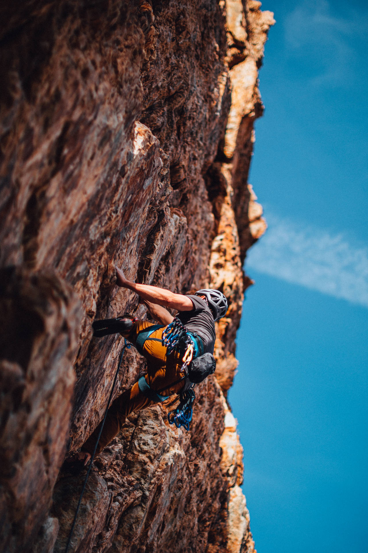 Man Rock Climbing Under A Blue Sky Wallpaper