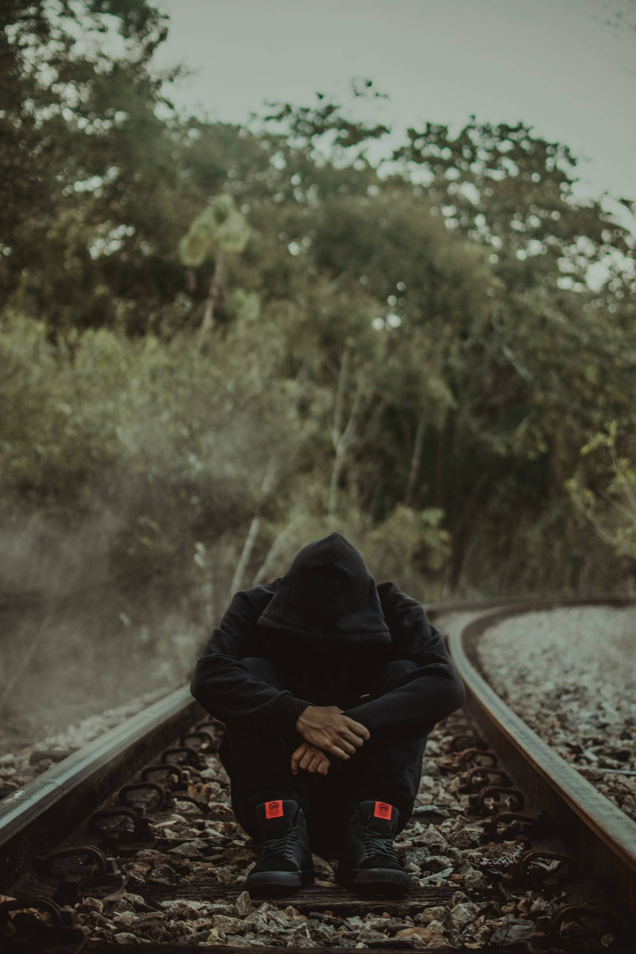 Man Sitting Alone On Railway Track Wallpaper