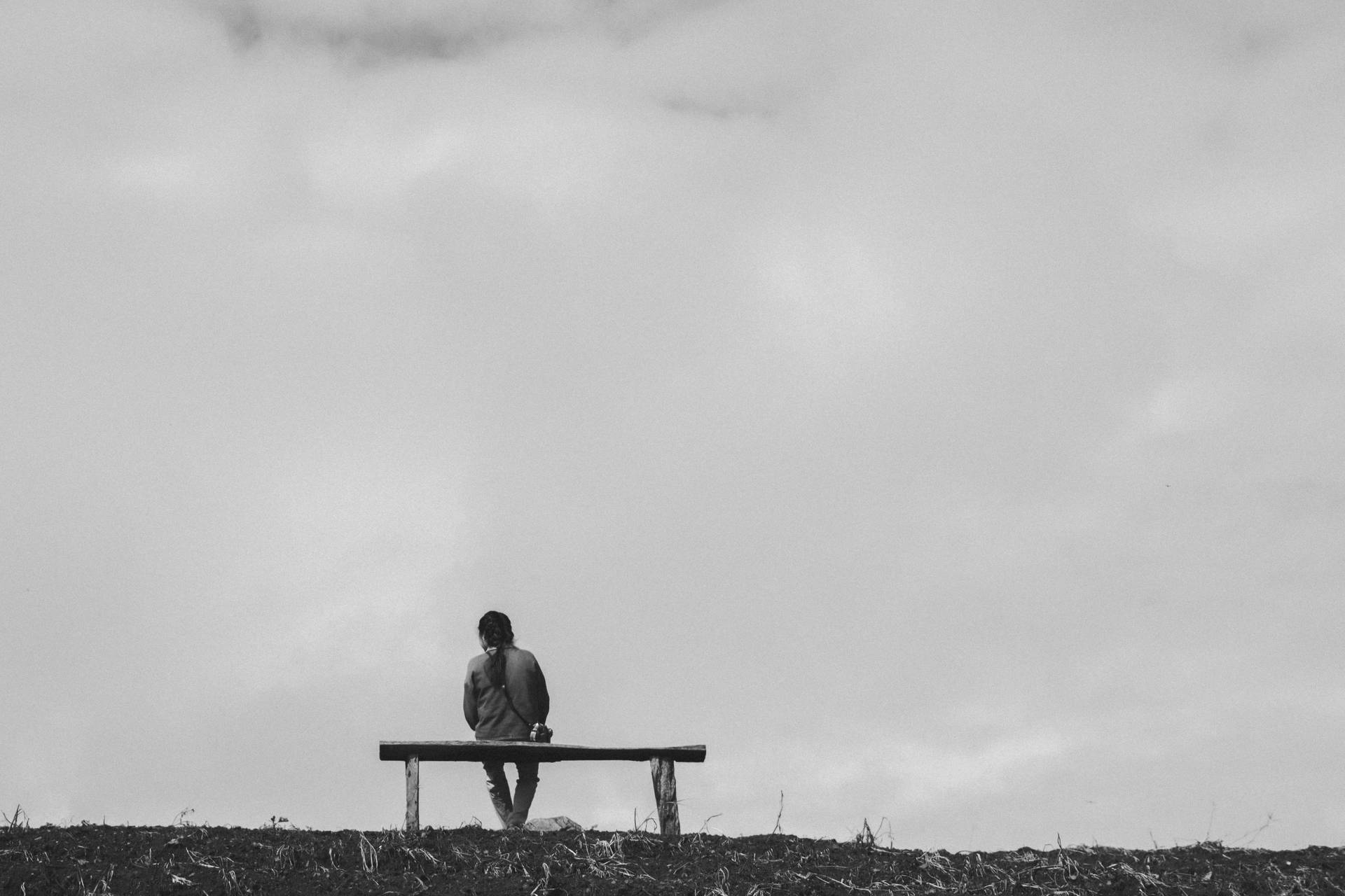 En mand sidder på bænken ved siden af en sø. Wallpaper