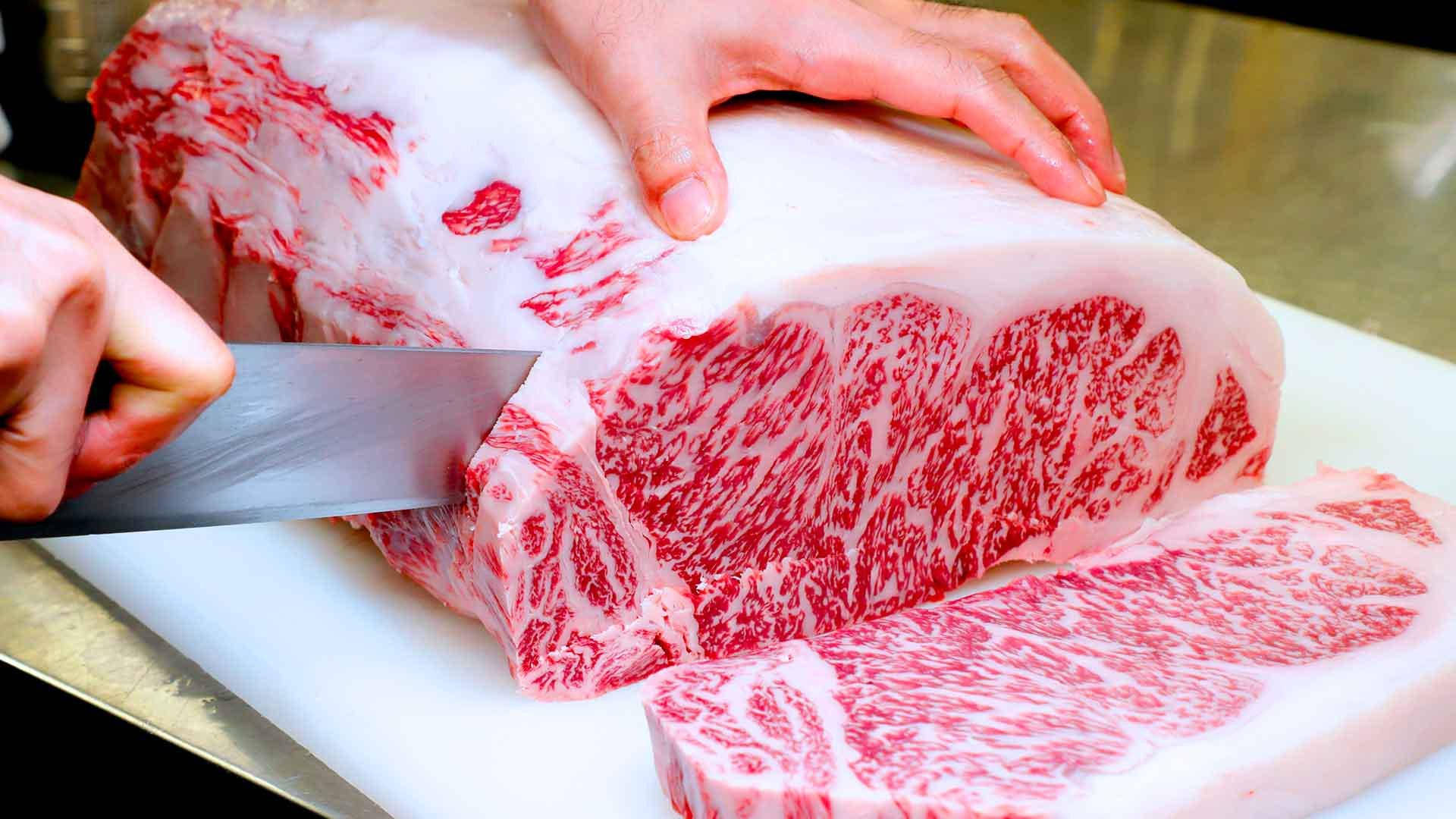 Man Slicing Sizeable Chunk Of Kobe Beef Wallpaper