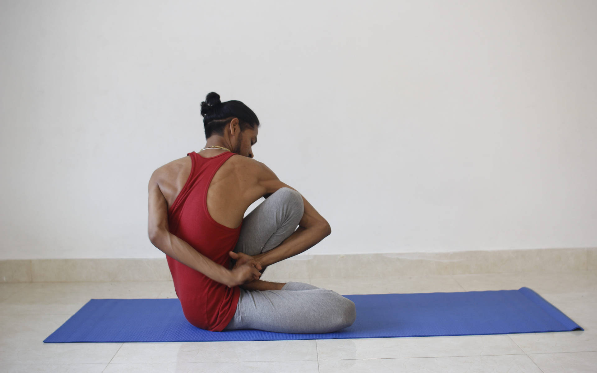 Hombrepracticando Yoga En Una Esterilla Azul Fondo de pantalla