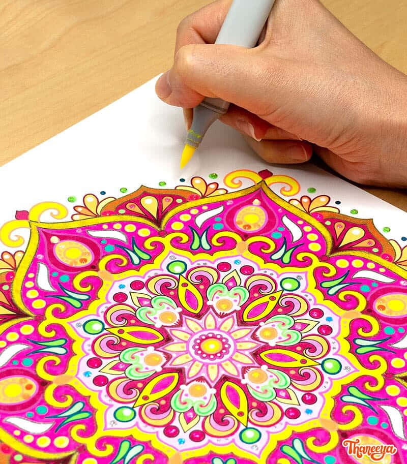 En person farver et mandala på papir.