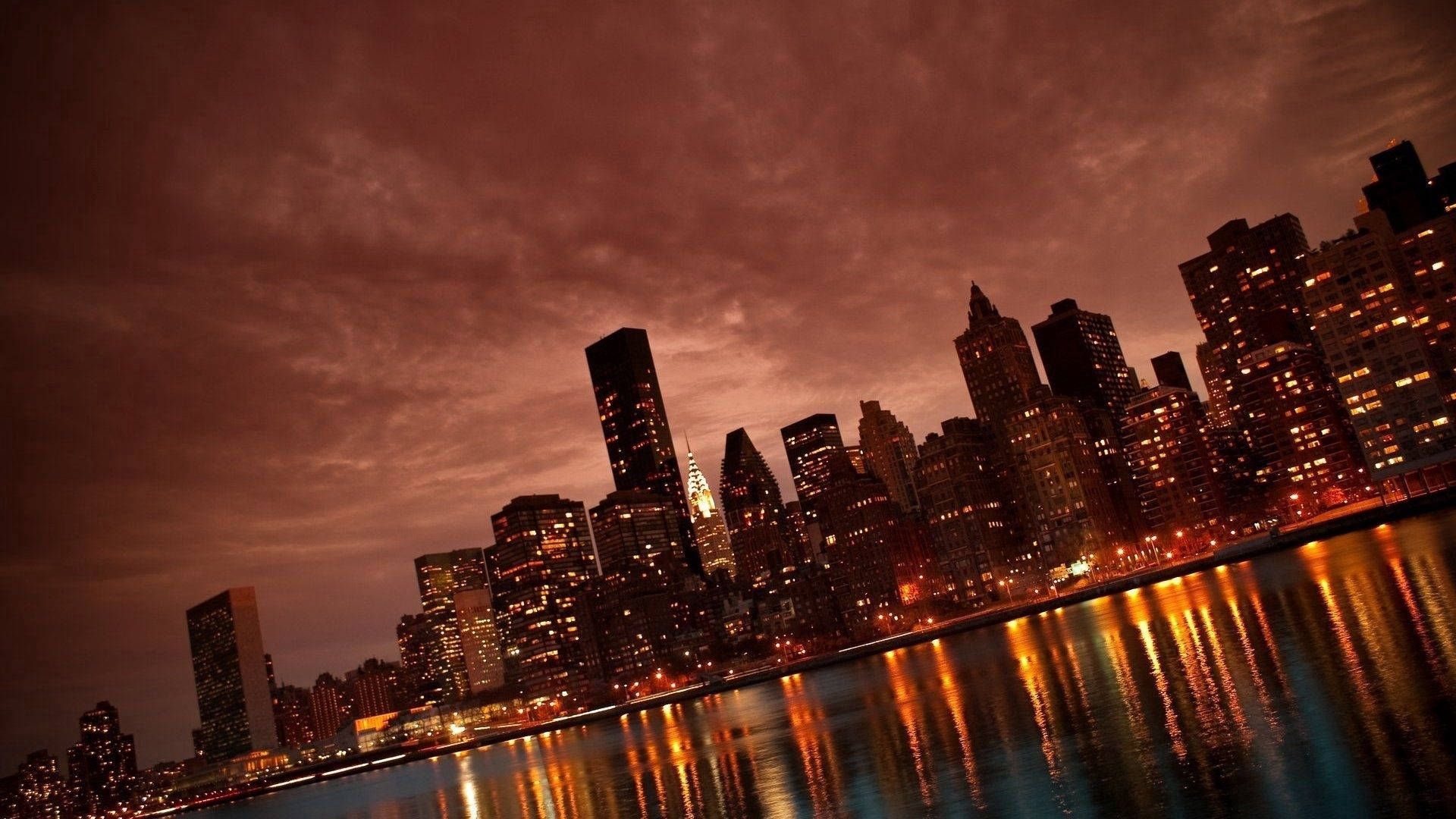 The iconic skyline of Manhattan reflecting over the East River. Wallpaper