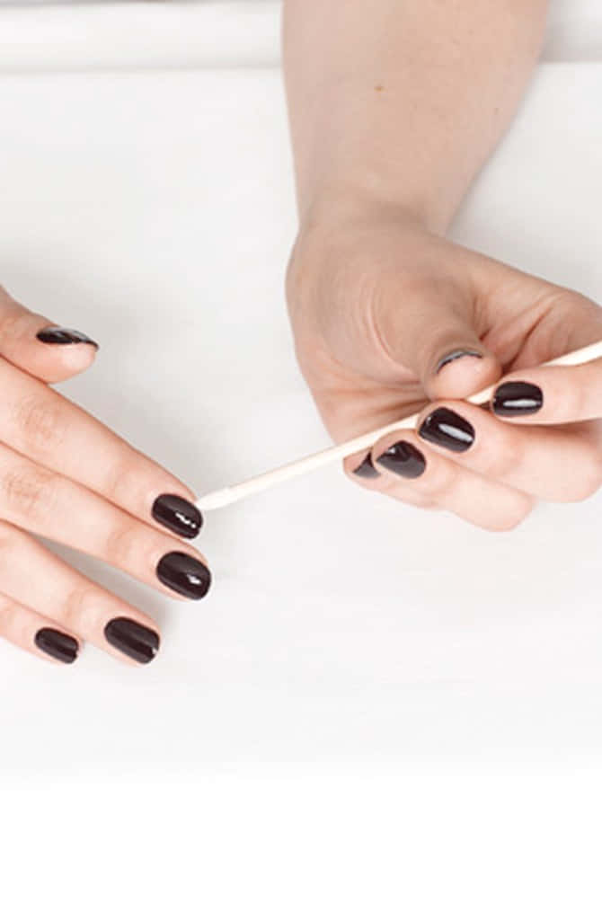 Download A Woman Is Holding A Black Nail Polish Brush | Wallpapers.com