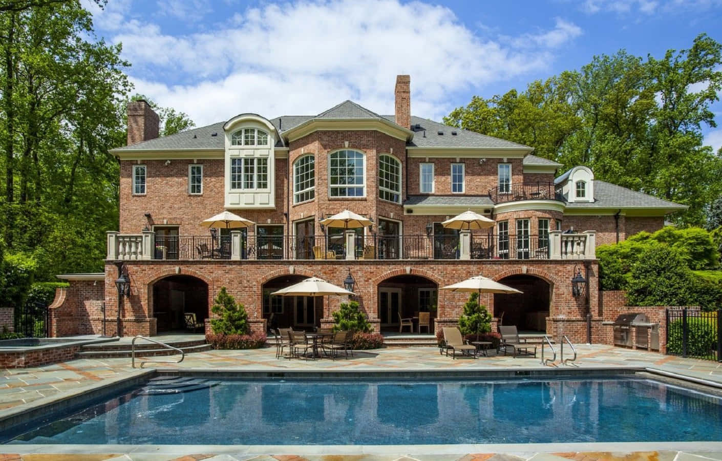 A Large Brick Home With A Pool And Patio