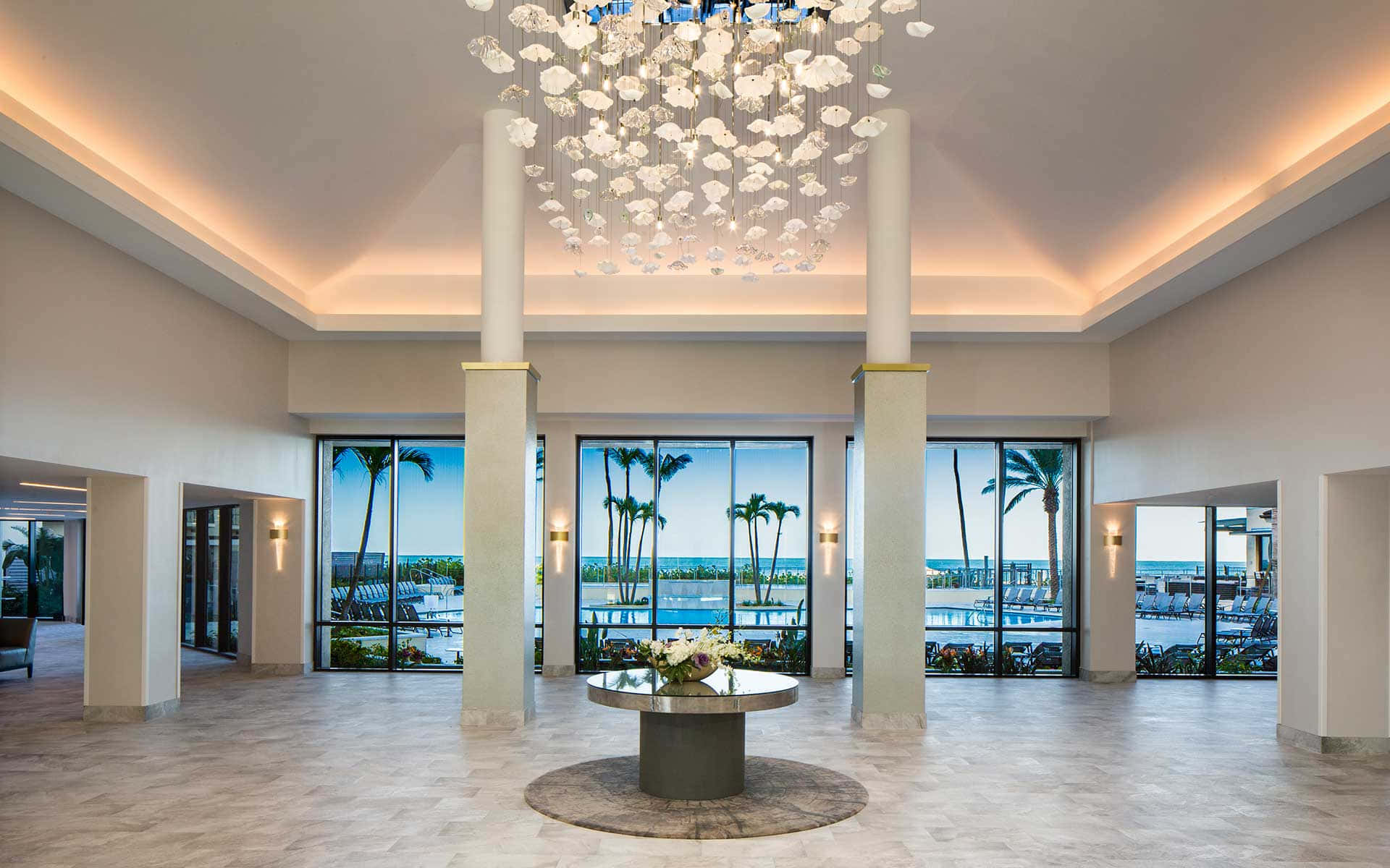 A Lobby With A Chandelier And Large Windows