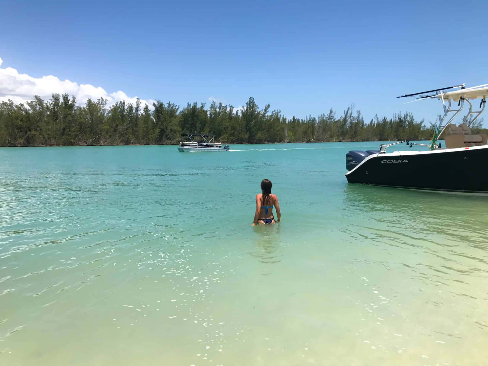 A Woman Standing In The Water Near A Boat