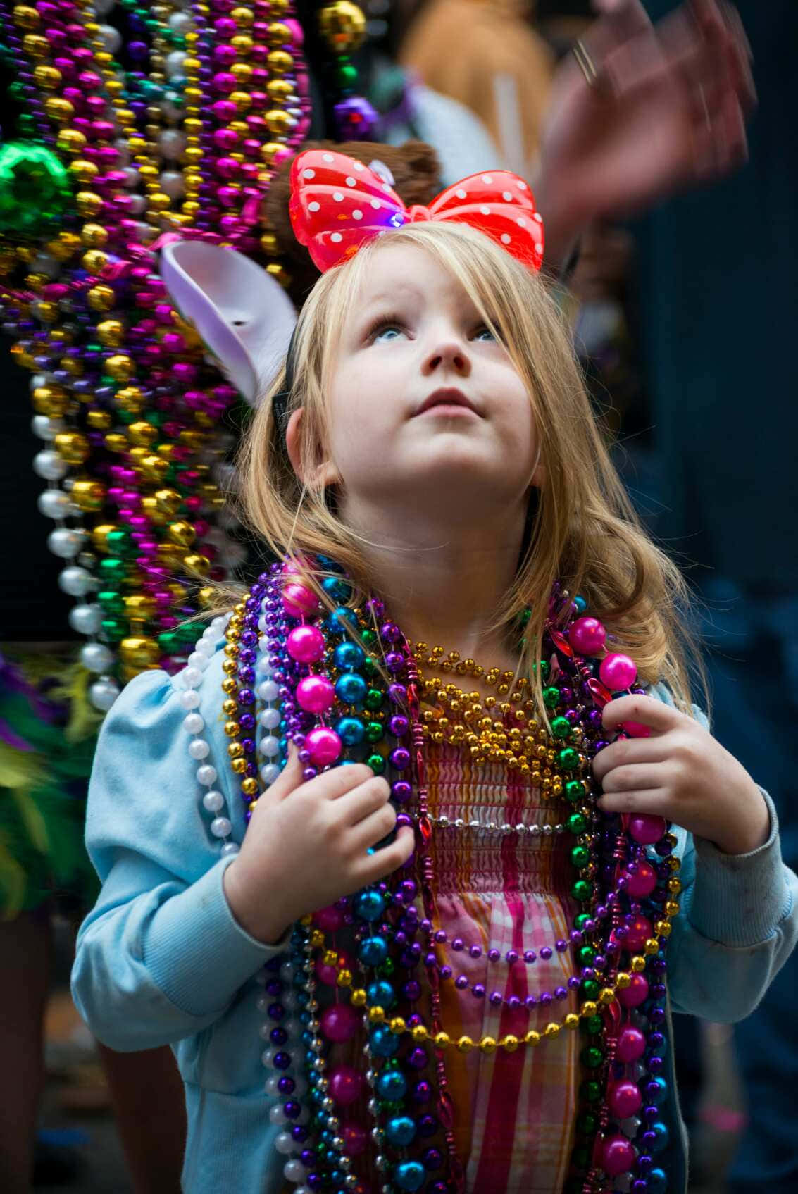 A Little Girl Wearing Beads And A Bow